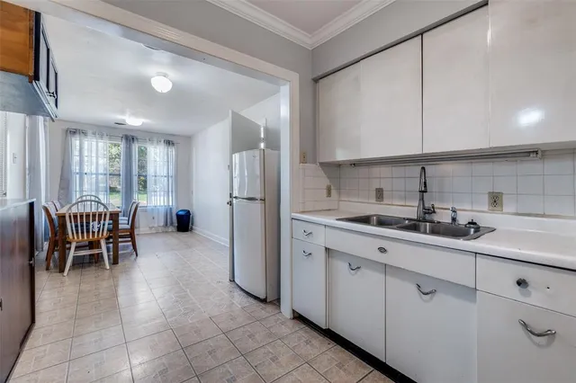 a kitchen with sink a refrigerator and chairs