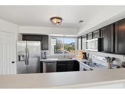 a kitchen with stainless steel appliances kitchen island granite countertop a sink refrigerator and cabinets