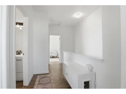 a view of a hallway with white walls and wooden floor