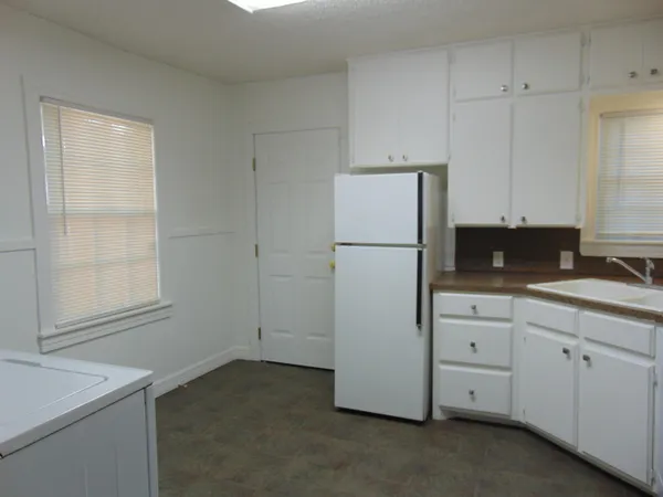 a kitchen with white cabinets and refrigerator