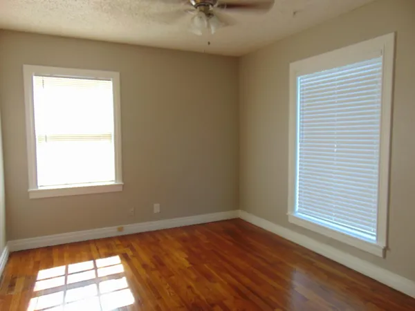 a view of an empty room with a window and wooden floor