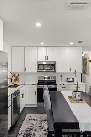 a kitchen with stainless steel appliances granite countertop a stove a sink a microwave a refrigerator and cabinets