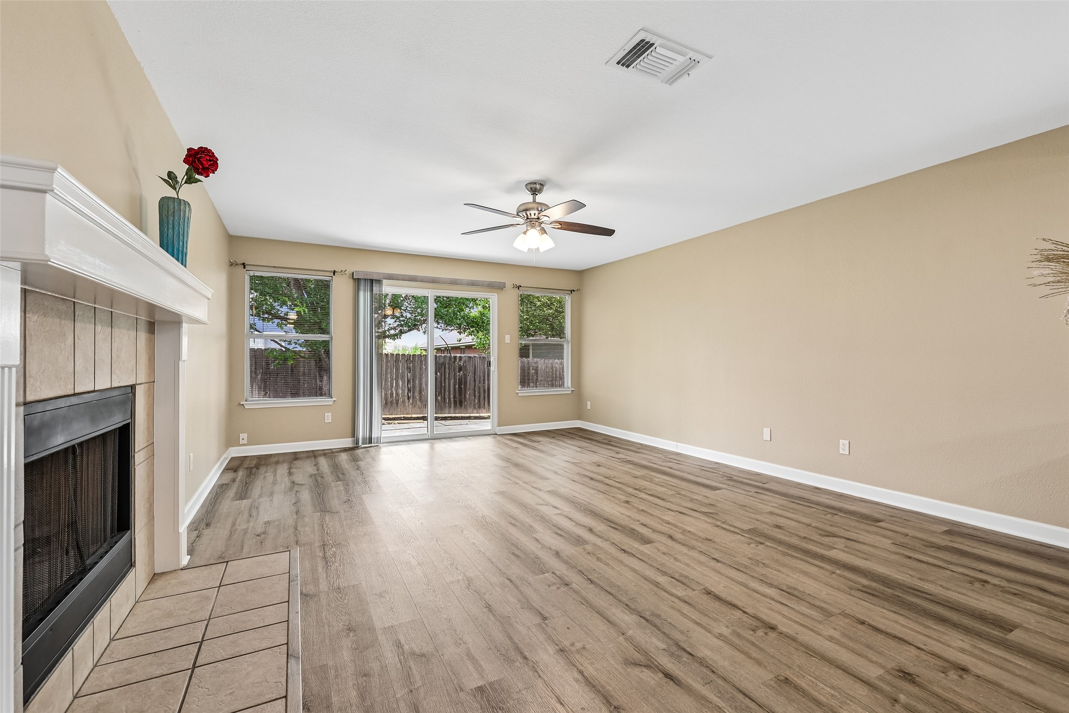 152 Grant Way Kyle, TX 78640 - Photo 10 of 39 an empty room with wooden floor fireplace and windows