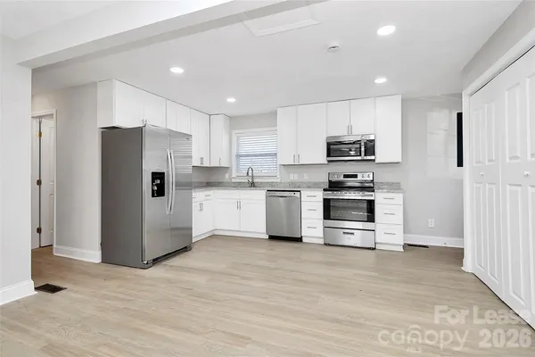 a kitchen with kitchen island white cabinets and stainless steel appliances