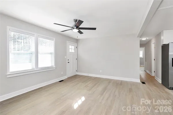 a view of empty room with wooden floor and fan