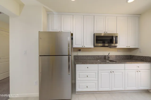 a kitchen with white cabinets and refrigerator