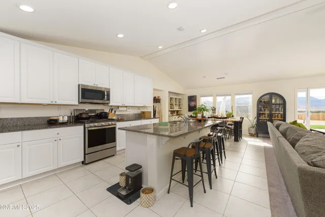 a kitchen with stainless steel appliances granite countertop a table and chairs in it
