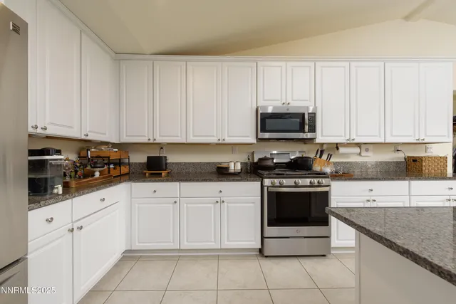 a kitchen with granite countertop white cabinets and stainless steel appliances