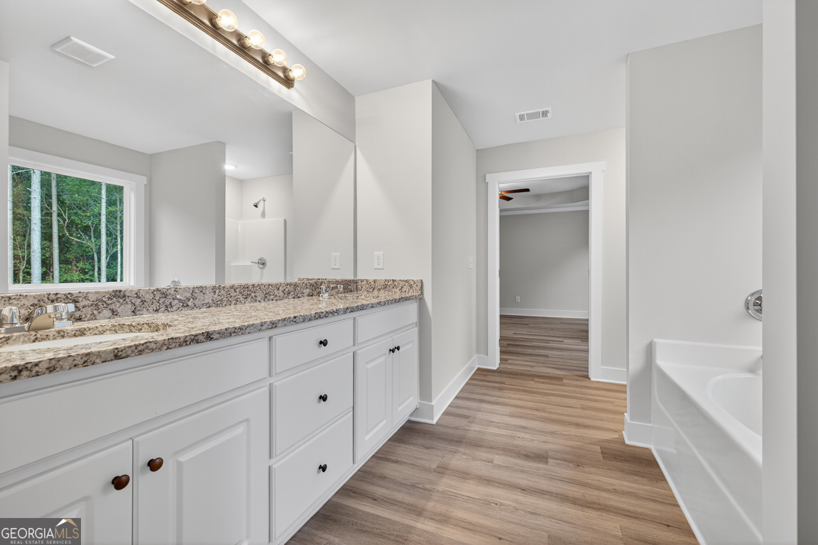 77 Sugar Maple Way, Unit 44 Colbert, GA 30628 - Photo 27 of 30 a spacious bathroom with a granite countertop sink and a bathtub