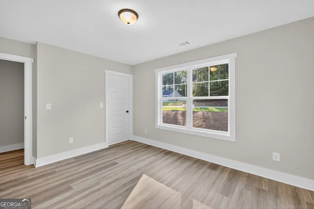 an empty room with wooden floor and windows
