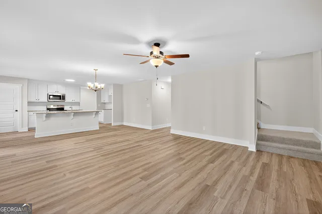 a view of an empty room with a kitchen and wooden floor