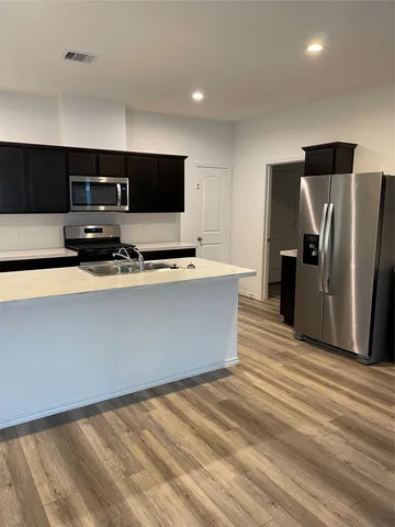 a room with stainless steel appliances a refrigerator and a television