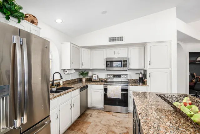 a kitchen with stainless steel appliances granite countertop a refrigerator sink and stove