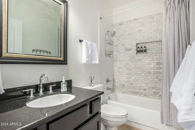 a bathroom with a granite countertop sink toilet a mirror a bathtub and shower