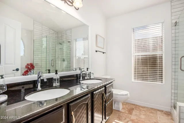 a bathroom with a granite countertop double vanity and a mirror