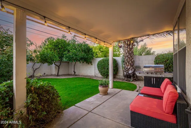 a backyard of a house with table and chairs potted plants and a large tree