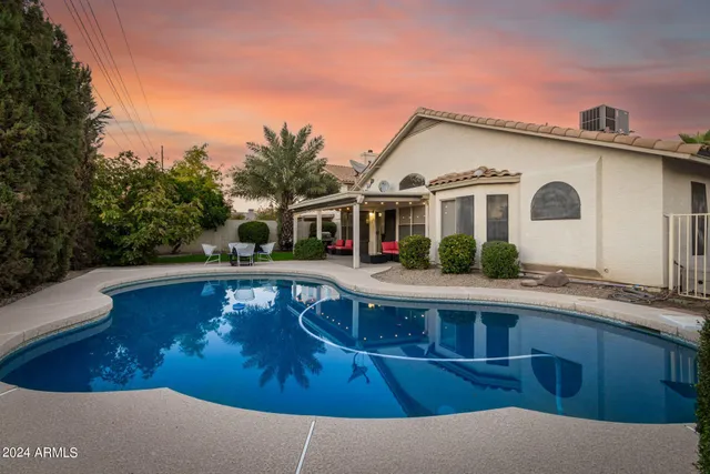 a view of house with swimming pool and a yard