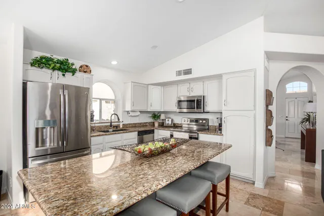 a view of a kitchen with kitchen island stainless steel appliances refrigerator stove microwave and cabinets