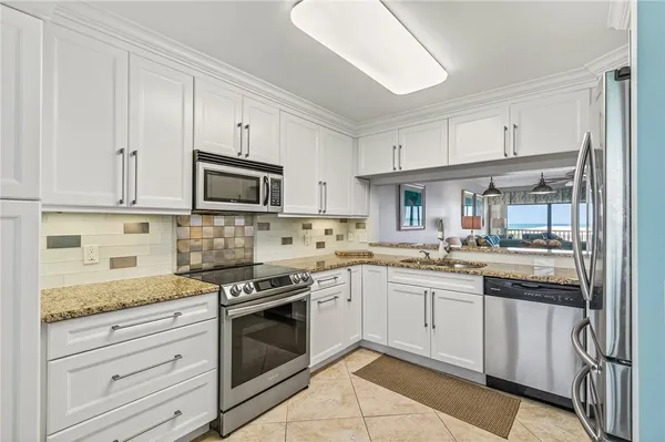 a kitchen with granite countertop white cabinets and stainless steel appliances