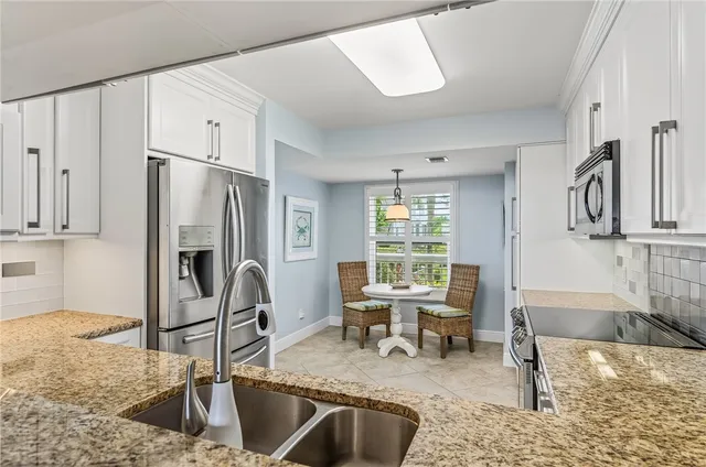 a kitchen with stainless steel appliances granite countertop a sink refrigerator and cabinets