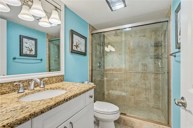 a bathroom with a granite countertop sink a toilet and a shower