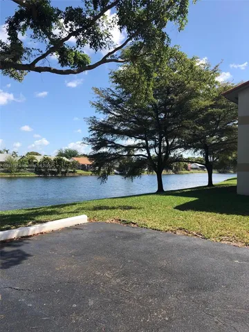 a view of a patio with table and chairs under an umbrella with a barbeque