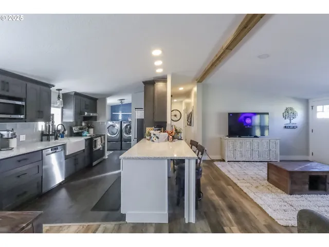 a living room with stainless steel appliances kitchen island furniture and a flat screen tv