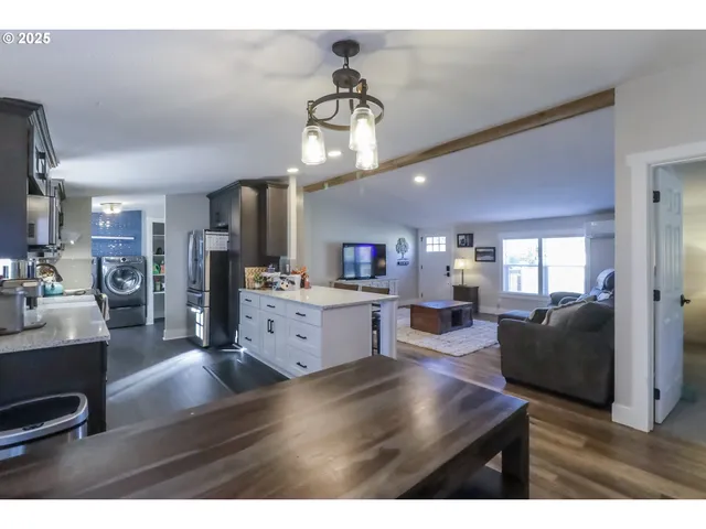 a living room with furniture kitchen view and a wooden floor