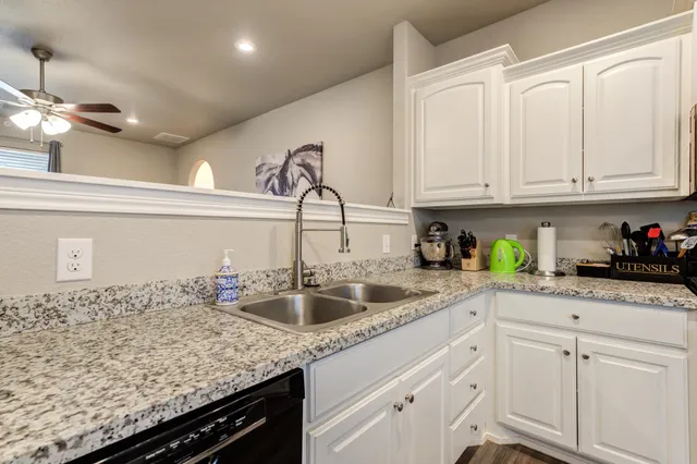 a kitchen with granite countertop a sink stainless steel appliances and white cabinets