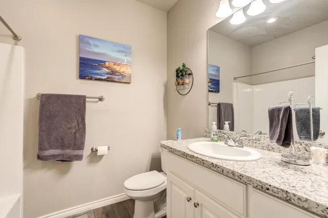 a bathroom with a granite countertop sink mirror vanity and toilet