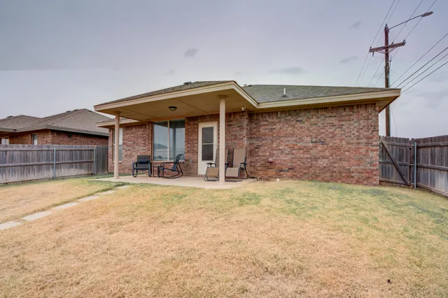 a view of a house with patio and wooden fence