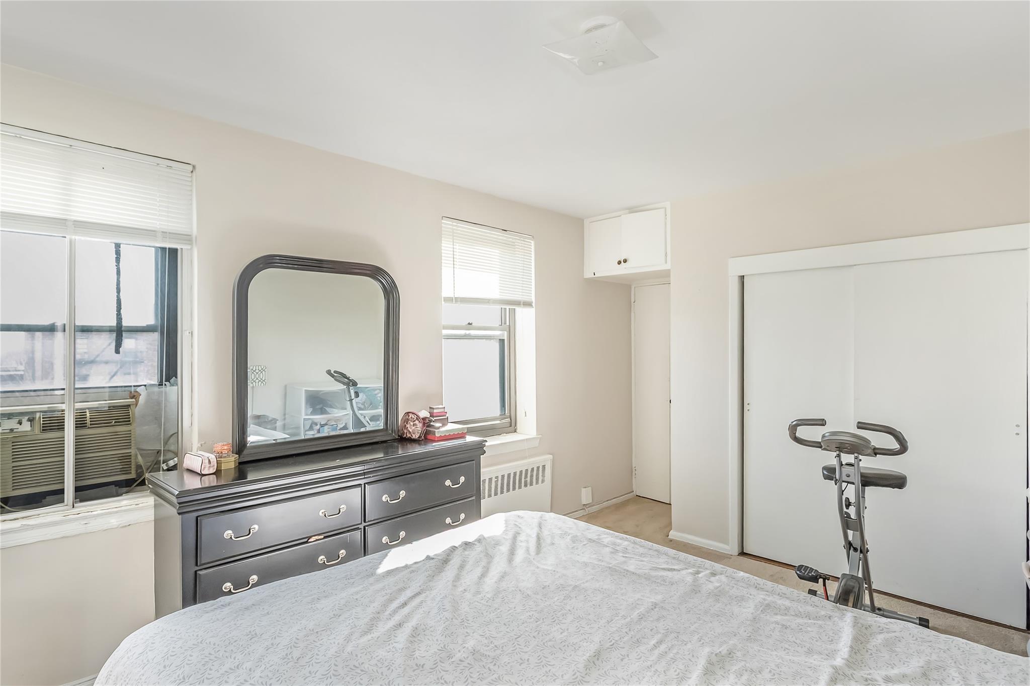 32-22 92nd Street, Unit 603 Queens, NY 11369 - Photo 16 of 25 a room with a bed and a mirror on dresser