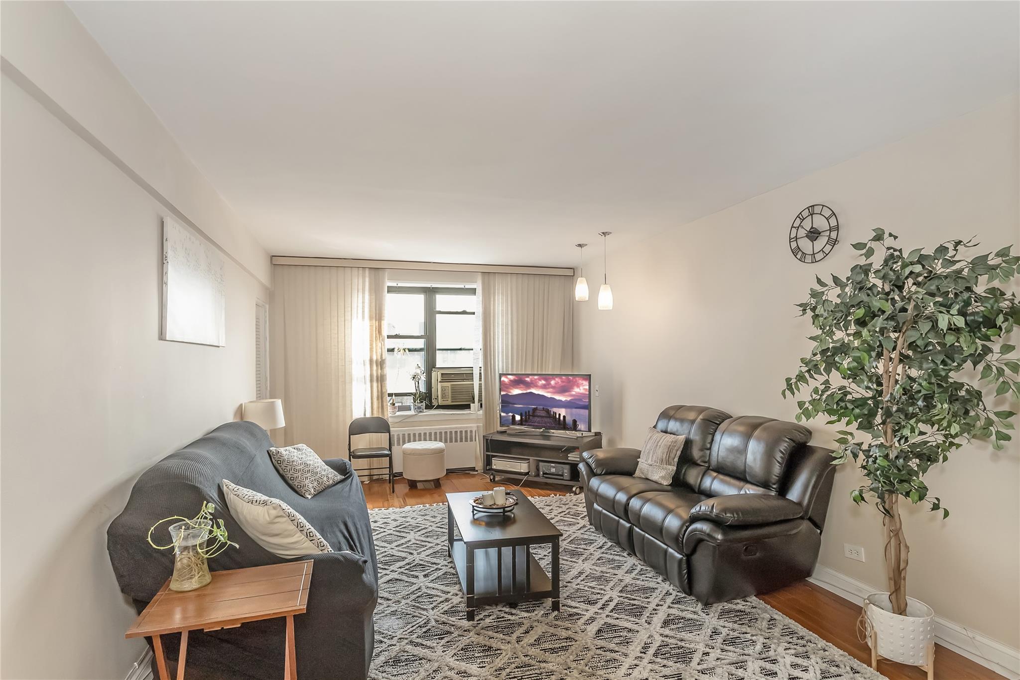 32-22 92nd Street, Unit 603 Queens, NY 11369 - Photo 7 of 25 a living room with furniture a flat screen tv and a window