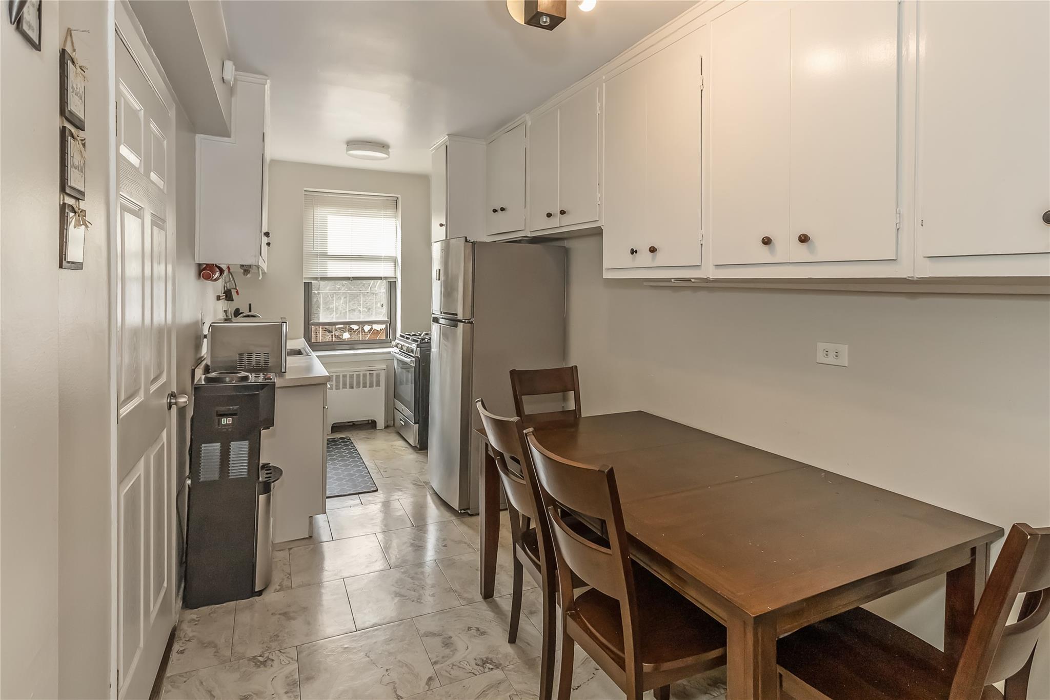 32-22 92nd Street, Unit 603 Queens, NY 11369 - Photo 10 of 25 a kitchen with a table chairs refrigerator and cabinets