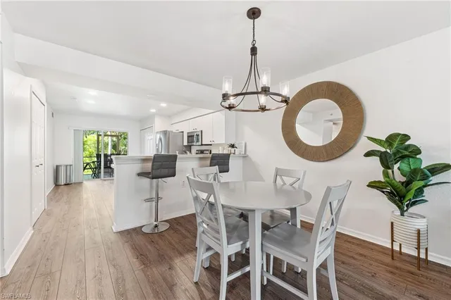 a view of a dining room and livingroom with furniture wooden floor a chandelier