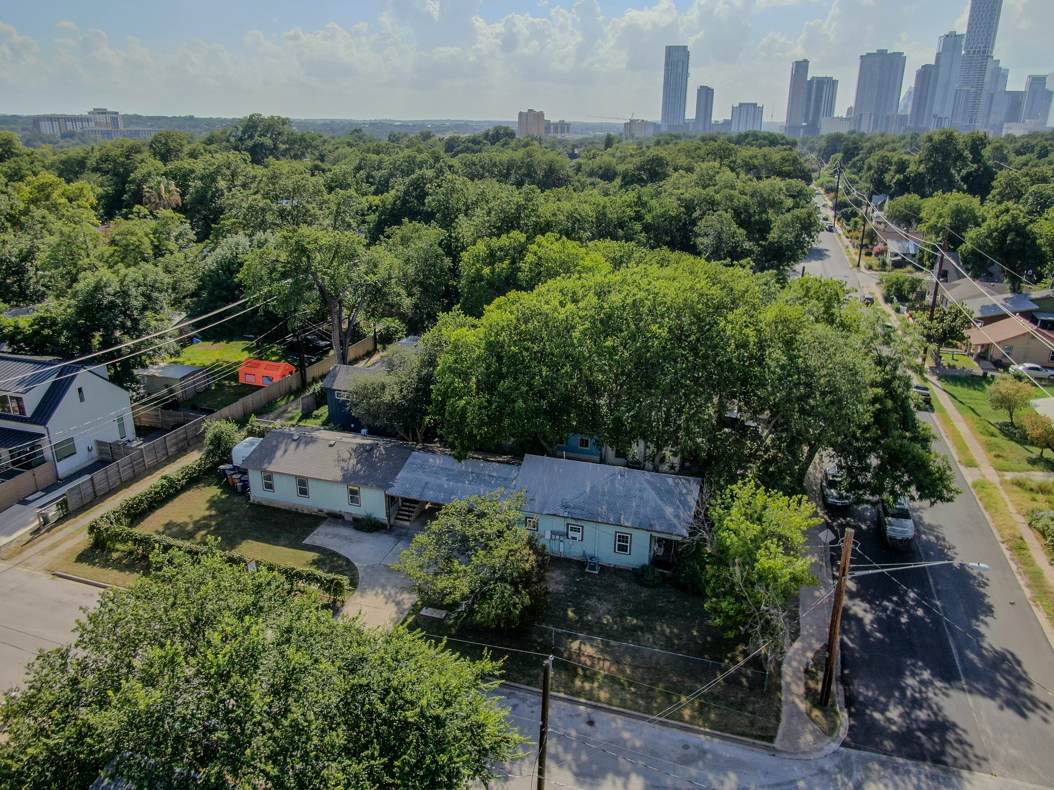 2015 Holly Street Austin, TX 78702 - Photo 1 of 24 An aerial perspective reveals a tree-lined neighborhood with glimpses of a distant cityscape.