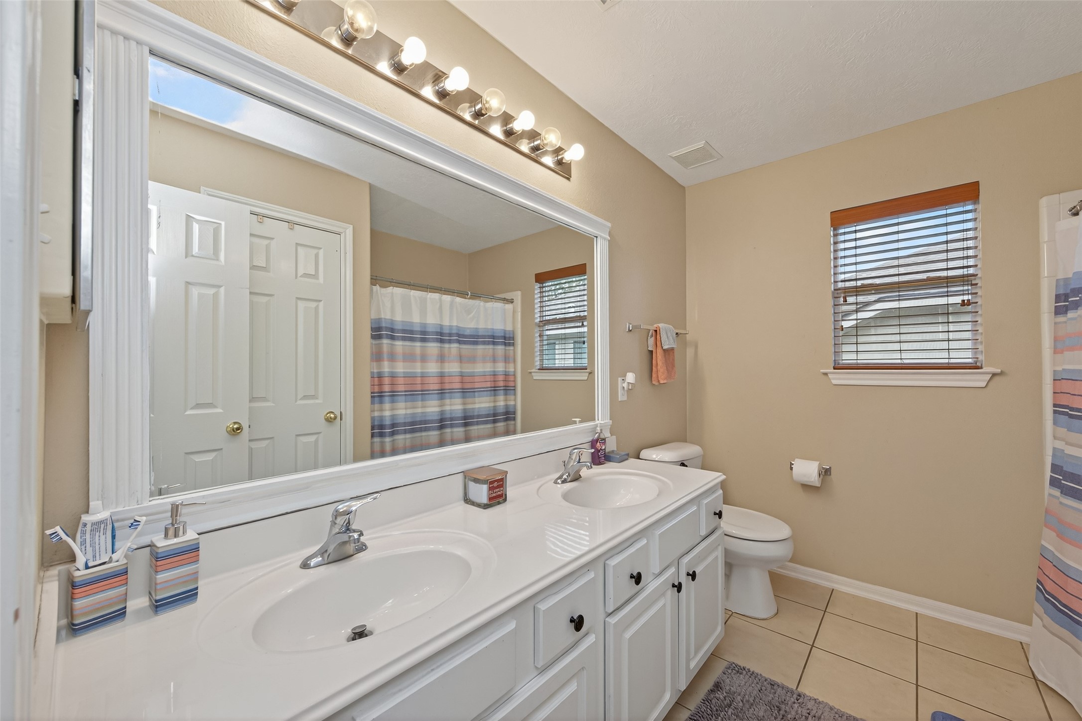 59 Genesee Ridge Drive Conroe, TX 77385 - Photo 25 of 44 a bathroom with a double vanity sink a toilet and a mirror