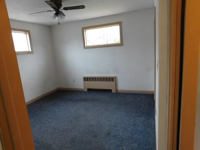 an empty room with a window and a fan