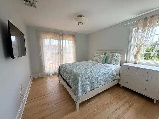 a bedroom with a large bed and a flat tv screen on dresser