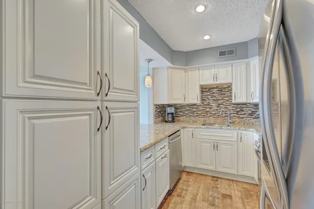a kitchen with stainless steel appliances granite countertop white cabinets and white appliances