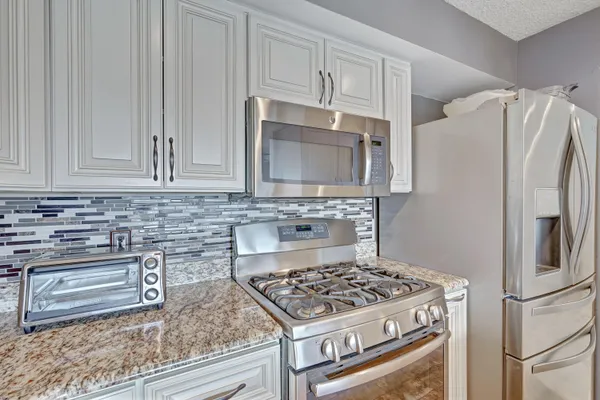 a kitchen with stainless steel appliances granite countertop a refrigerator stove and cabinets