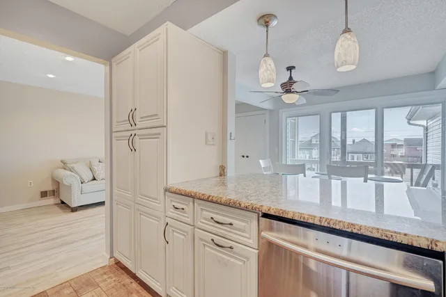 a very nice looking kitchen with granite countertop a sink white cabinets and a large window