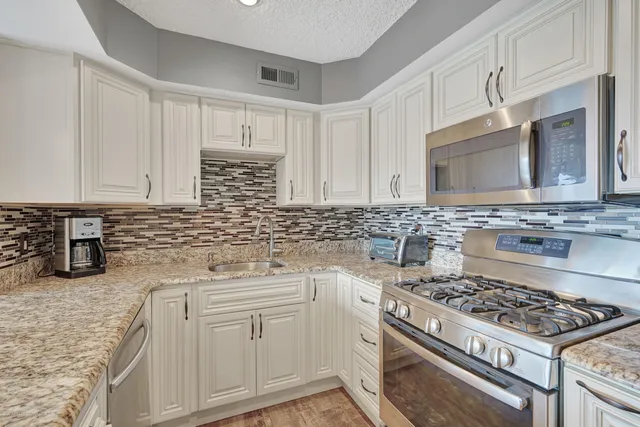 a kitchen with white cabinets and appliances