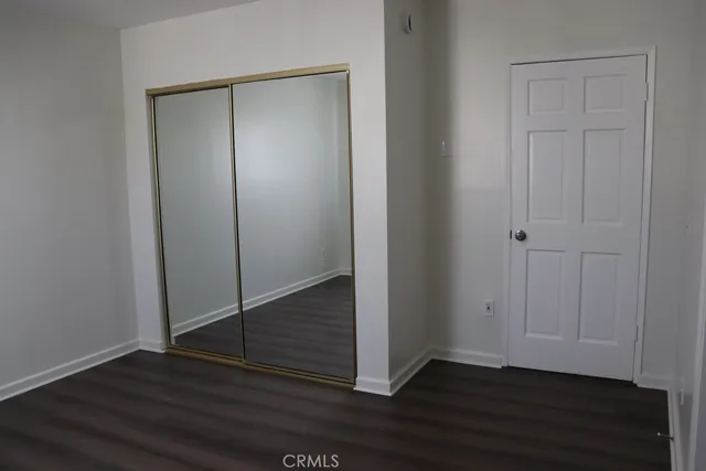 an empty room with wooden floor and windows with curtains