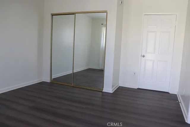 a view of an empty room with wooden floor and closet