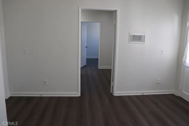 an empty room with wooden floor and windows with curtains