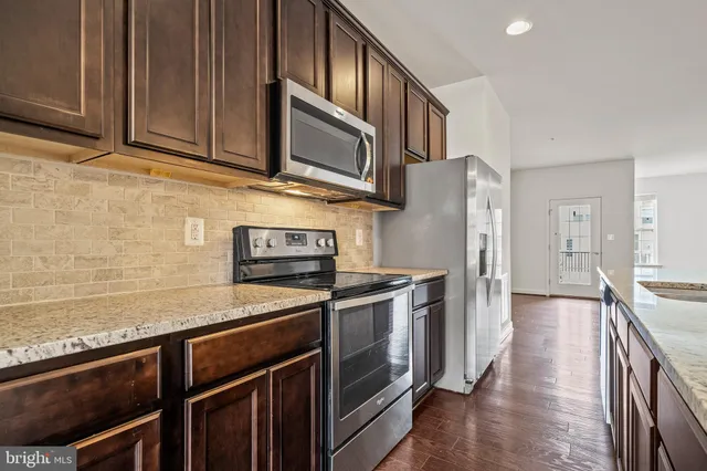 a kitchen with stainless steel appliances granite countertop a refrigerator stove and sink