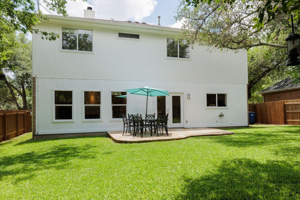 7136 Ridge Oak Road Austin, TX 78749 - Photo 4 of 40 A verdant lawn extends from a broad patio, perfect for outdoor dining and enjoying the generous yard.