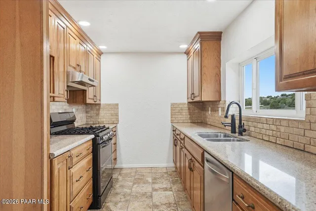a kitchen with stainless steel appliances granite countertop a sink stove and cabinets