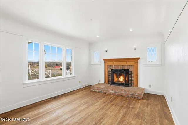 an empty room with windows and fireplace